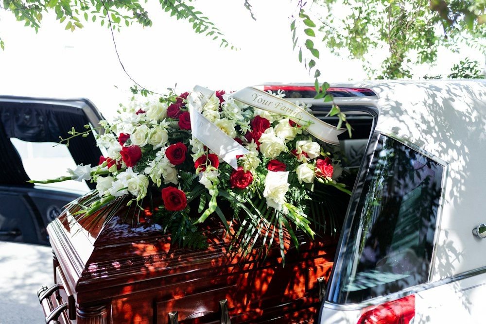A casket covered with red and white flowers at a funeral